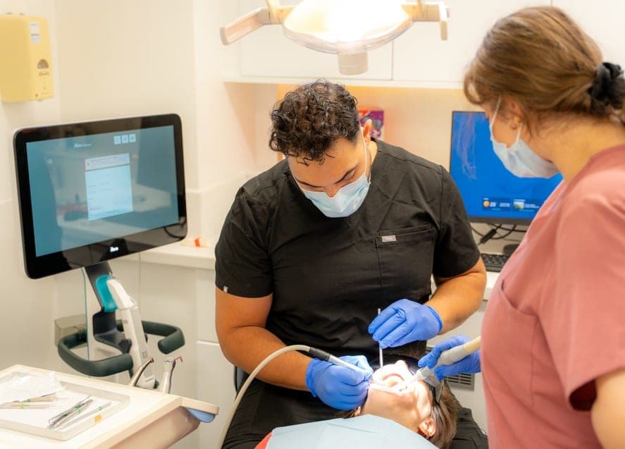 A dentist and dental nurse treating a patient in one of the practice’s surgeries
